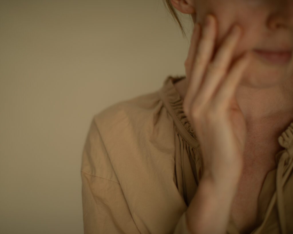 Gentle hand resting against the face in a moment of stillness and presence