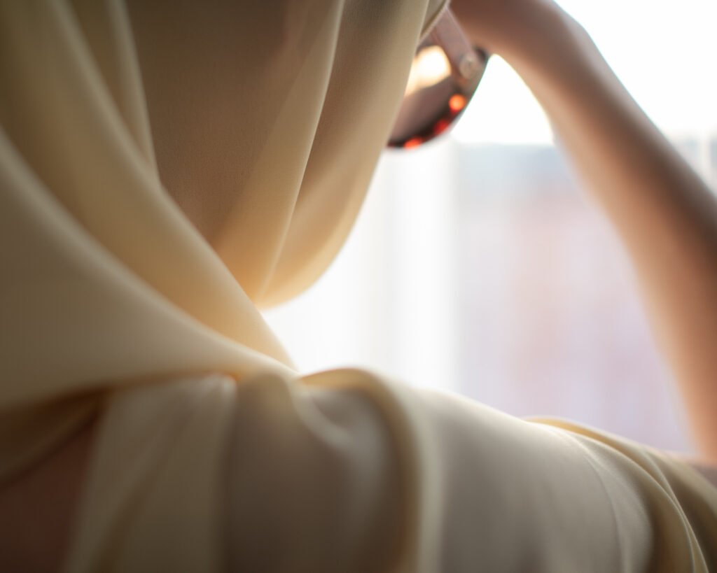 Close cinematic detail of cream scarf and luxury sunglasses near window light