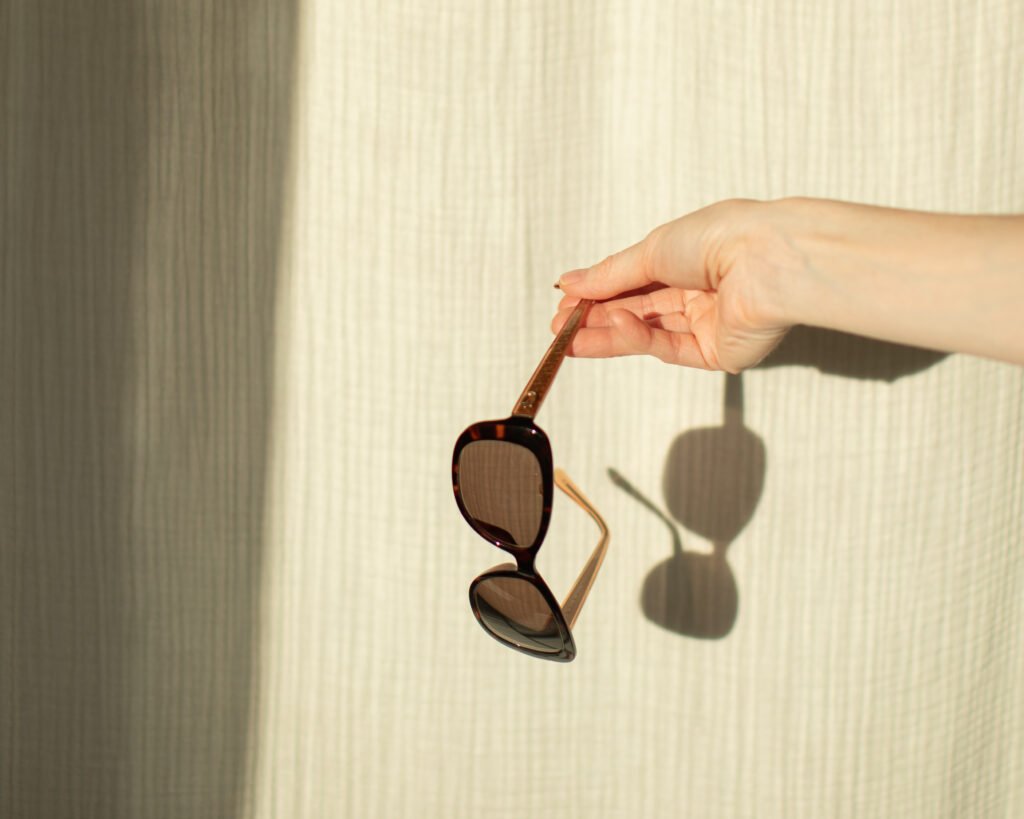 Luxury eyewear still life by Anya Baro featuring sunglasses and hand shadows in natural light.