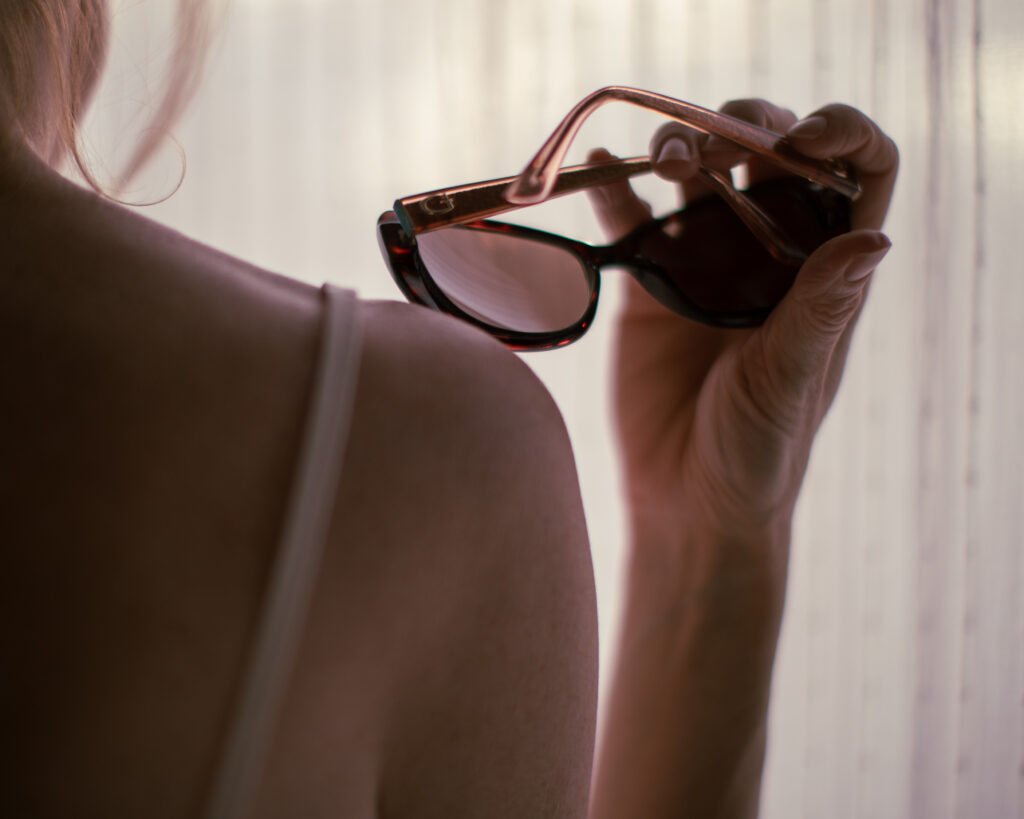 Luxury sunglasses held in warm sunlight near window shadows