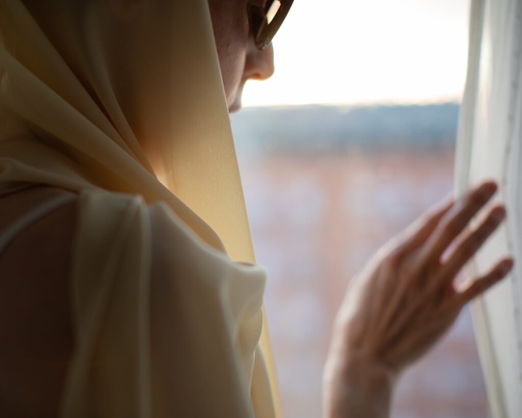 Slow luxury cinematic portrait with hand gesture near a window and cream scarf