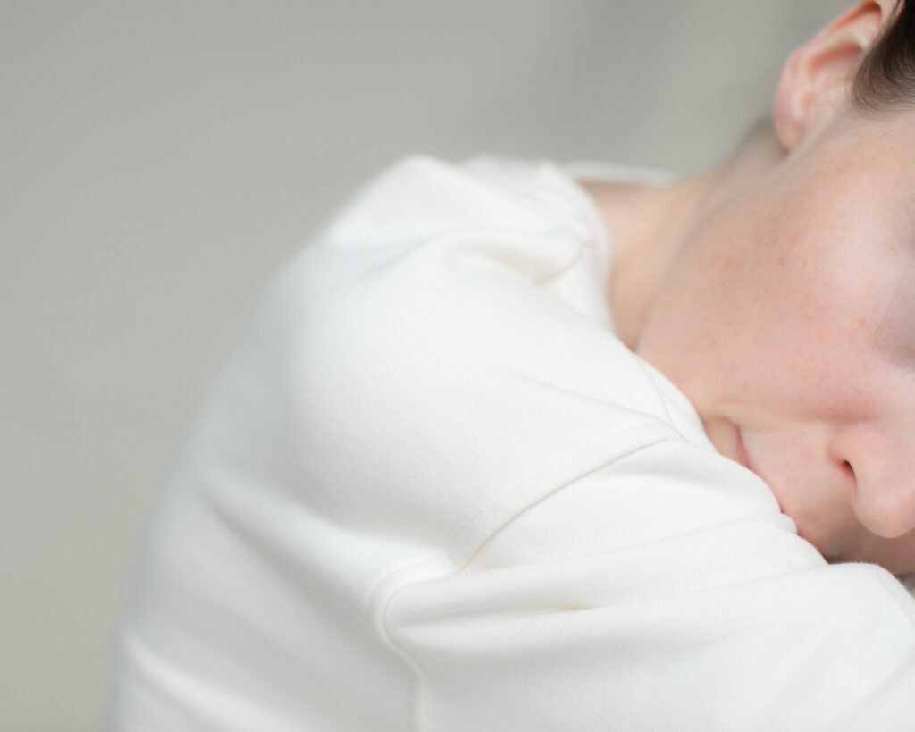Woman resting against a pillow in diffused daylight.
