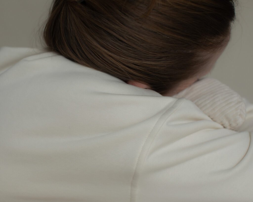 Back view of a woman leaning into a cushion in a quiet interior.